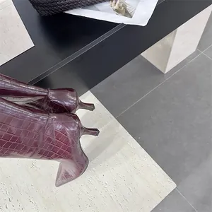 Detailed macro view of burgundy stone-patterned high boots featuring chic stiletto heels