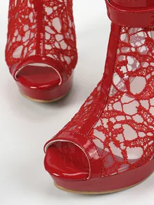 Gros plan sur la dentelle rouge et le cuir verni brillant des sandales à plateforme.