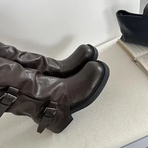 Nahaufnahme brauner Leder-Westernstiefel mit Metallschnalle und Faltenstruktur