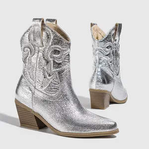 Detailed macro view of retro silver metallic cowboy boots with intricate embroidery
