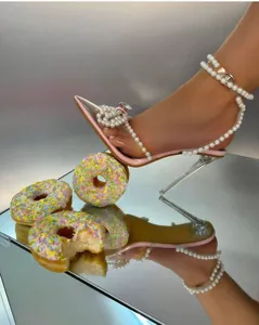 Λεπτομέρεια κομψών ροζ διαφανών τακουνιών με φιόγκο από πέρλες πάνω σε καθρέφτη