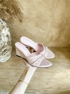 Dettaglio di sandali con zeppa rosa con borchie argentate e trama in camoscio.