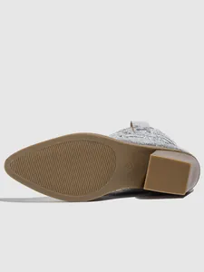 Close-up detail of the anti-slip brown sole and block heel on a silver metallic cowboy boot.