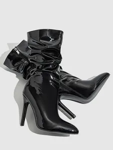 Detailed view of high-shine black patent leather slouchy stiletto boots with pointed toe.