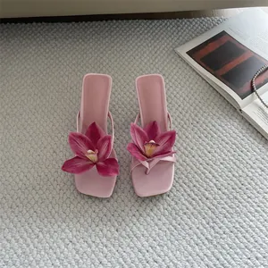 Detailed view of pink high-heeled sandals with large purple orchid floral ornaments