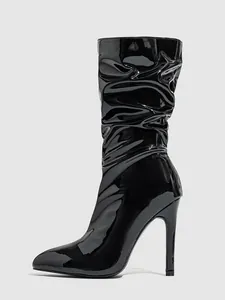 Detailed view of fashionable black patent leather slouched boots with stiletto heels