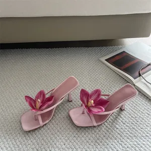 Detail of elegant pink thong sandals featuring oversized orchid flower decoration.
