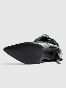Detailed sole and heel view of a black patent leather slouchy stiletto boot with pointed toe
