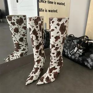 Close-up of stylish cow print knee-high boots with pointed toe and stiletto heels