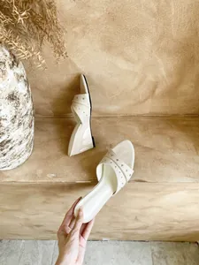 Dettaglio di sandali beige con zeppa ed eleganti borchie argentate.