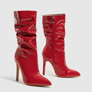 Detail of red patent leather mid-calf boots with stiletto heels and pleated design