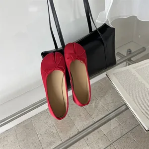 Close-up detail of stylish red split-toe tabi flats with elegant bow on a glass table