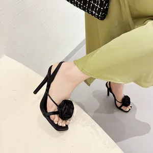 Detail of black silk high heel sandals with an elegant rose flower on the toe strap.