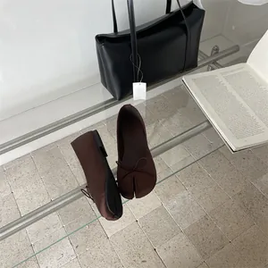 Detailed view of dark brown split-toe Tabi ballet flats featuring a delicate bow accent