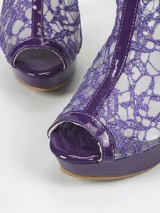Gros plan montrant la maille en dentelle violette et le cuir verni sur les sandales à plateforme.