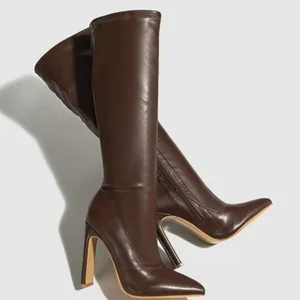 Detailed side view of dark brown knee-high boots with pointed toe and stiletto heel