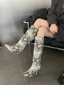 Detailed view of stylish knee-high python print boots with pointed toe and slim heel