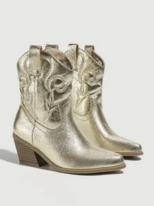 Detailed macro view of golden metallic western boots with retro embroidery patterns
