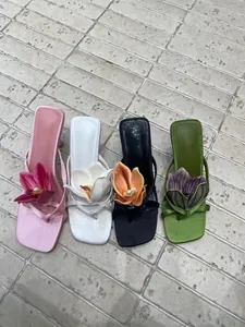 Detail view of four colored Mori style thong high heel slippers with large floral decor.