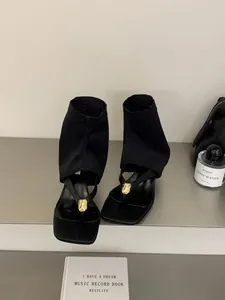 Sandalias de dedo negras con punta cuadrada, caña elástica y adorno dorado.