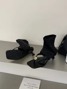 Detalle de botines calcetín negros con punta cuadrada y un elegante detalle dorado