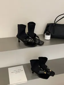Detalle de botines negros de tacón con punta cuadrada y diseño de sandalia de dedo