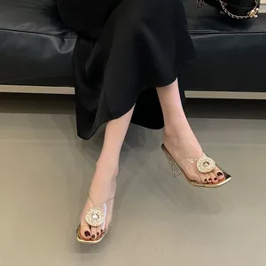 Close-up detail of women's transparent PVC high heel slippers with rhinestone buckle