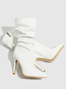 Detailed view of stylish white patent leather slouchy boots with high stiletto heels