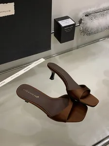 Dettaglio di eleganti sandali in raso marrone con punta quadrata e tacco a spillo chic.