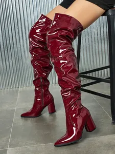 Detail of burgundy patent leather slouchy thigh-high boots with chunky heel and side zip
