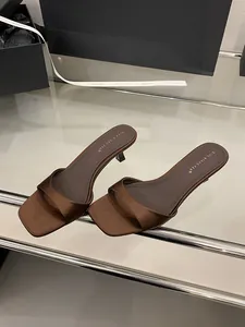 Dettaglio di sabot in raso marrone con tacco alto e design minimalista a punta quadrata