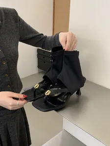 Primer plano de sandalias negras de tacón alto con elegantes detalles dorados.