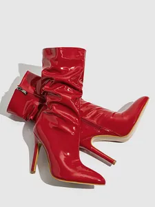 Close-up of bright red patent leather stiletto boots featuring a slouchy ruched design