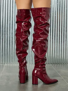 Macro detail of wine red patent leather slouchy thigh-high boots with block heel