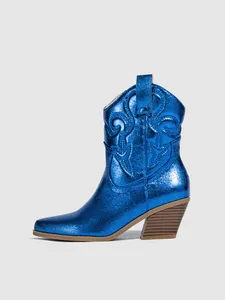 Side view detail of a metallic blue cowboy boot with embroidered patterns and chunky heel.
