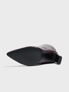 Detail view of the black non-slip sole and block heel of a burgundy pointed-toe boot.