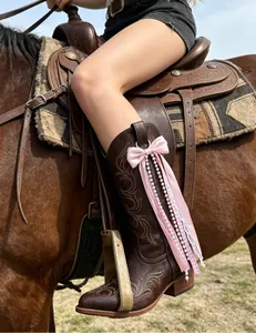 Close-up detail of a pink ribbon bow boot pendant with white pearls and lace tassels