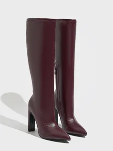 Detailed side view of burgundy pointed-toe knee-high leather boots with chunky heels