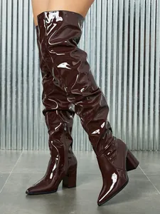 Detail of burgundy patent leather thigh-high boots with pointed toe and chunky heel