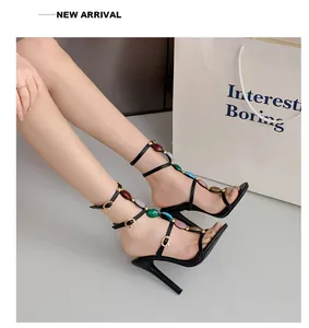 Detailansicht eleganter schwarzer T-Riemchen-Sandalen mit bunten Schmucksteinen.