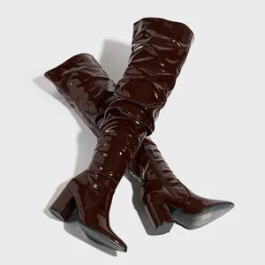 Close-up of burgundy patent leather over-the-knee slouchy boots with chunky heels