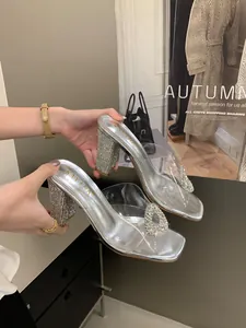 Close-up of elegant silver block heel sandals with rhinestone buckle and PVC upper.