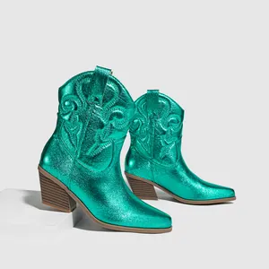 Close-up view of metallic turquoise western cowboy boots with vintage floral embroidery.