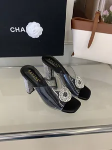 Close-up of elegant PVC transparent mules with sparkling rhinestone buckles and block heels