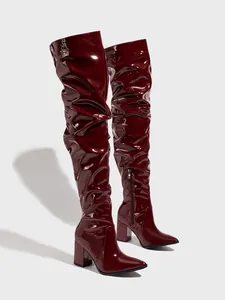 Detail view of burgundy patent leather slouchy thigh-high boots with chunky heel