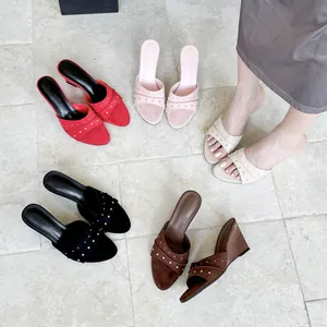 Eleganti sandali con zeppa e borchie da donna in vari colori su pavimento in piastrelle