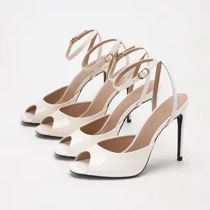 Cream patent leather peep toe stiletto sandals with elegant ankle straps for women.
