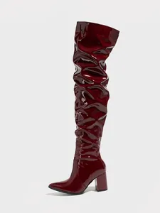 Detailed macro view of burgundy patent leather thigh-high boot with slouchy shaft design