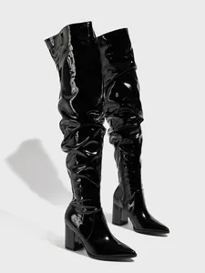 Detail view of black patent leather slouchy thigh-high boots with pointed toe and block heel