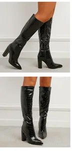 Detailed view of black croc-embossed knee-high boots with pointed toe and chunky heel.